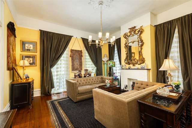living area with baseboards, a brick fireplace, an inviting chandelier, and hardwood / wood-style flooring