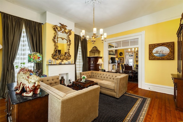 living area with baseboards, a chandelier, built in shelves, and dark wood-style floors