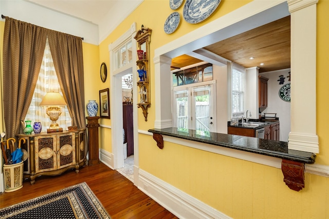 interior space featuring baseboards, ornate columns, a sink, and wood finished floors