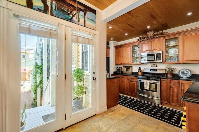 kitchen featuring brown cabinetry, wooden ceiling, a wealth of natural light, and stainless steel appliances