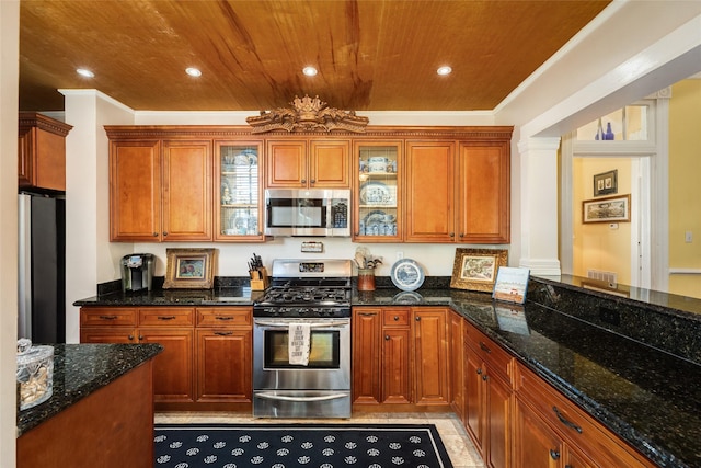 kitchen with glass insert cabinets, wooden ceiling, decorative columns, brown cabinetry, and stainless steel appliances