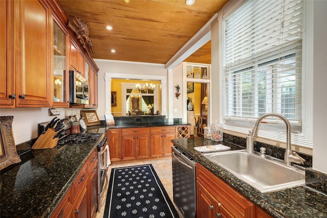 kitchen featuring glass insert cabinets, a notable chandelier, a sink, appliances with stainless steel finishes, and brown cabinets