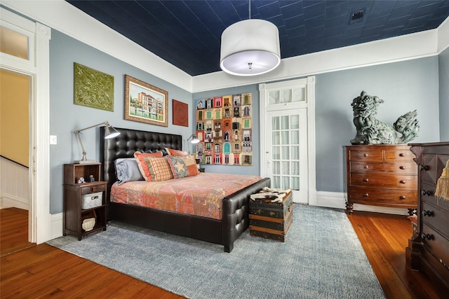 bedroom with visible vents, hardwood / wood-style flooring, and baseboards
