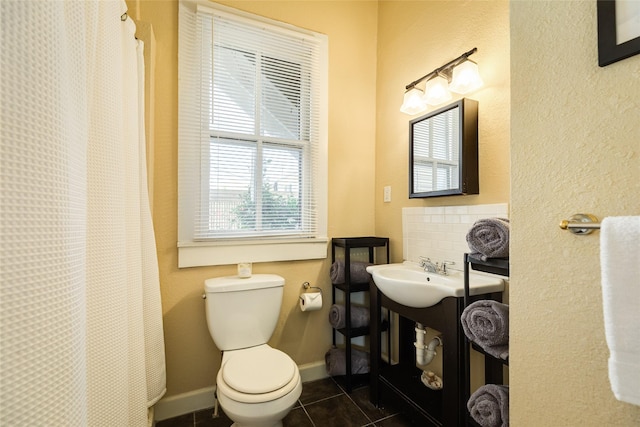 bathroom featuring tile patterned flooring, toilet, curtained shower, a sink, and decorative backsplash