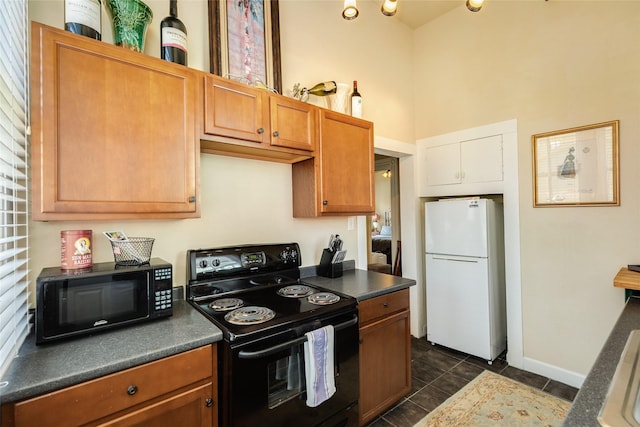 kitchen with a towering ceiling, black appliances, dark countertops, brown cabinets, and baseboards