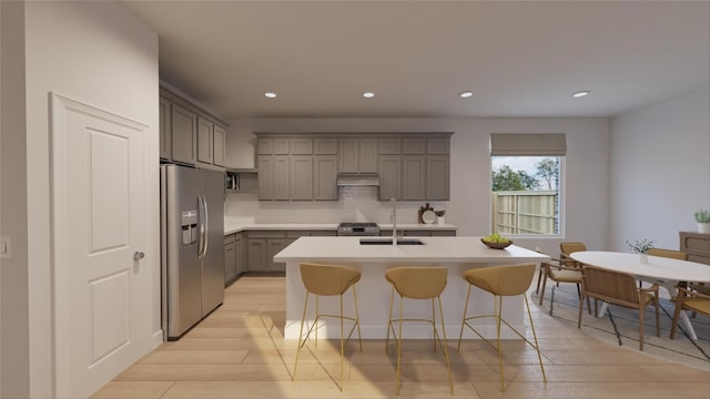 kitchen with light wood-type flooring, gray cabinetry, decorative backsplash, stainless steel appliances, and a sink