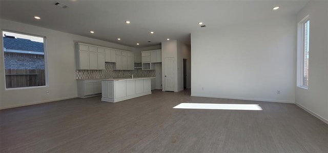 5823 Starling Dr, Baytown, TX 77521 - kitchen featuring backsplash, wood finished floors, open floor plan, a center island with sink, and baseboards