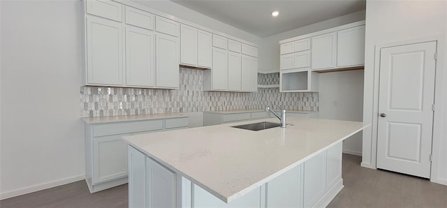 5823 Starling Dr, Baytown, TX 77521 - kitchen featuring a sink, wood finished floors, an island with sink, decorative backsplash, and baseboards