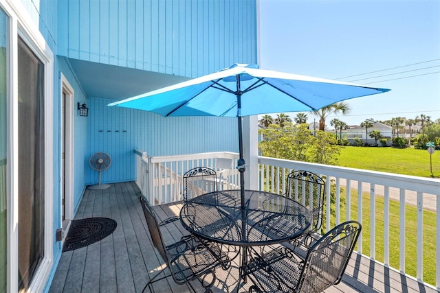 deck featuring outdoor dining area and a lawn