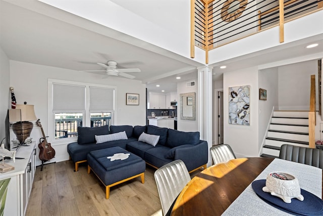 living room featuring light wood-style floors, ceiling fan, visible vents, recessed lighting, and stairway