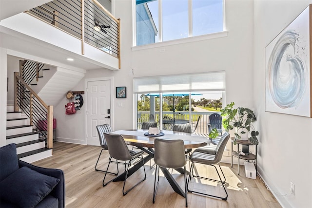 dining room with stairs, a high ceiling, baseboards, and wood finished floors