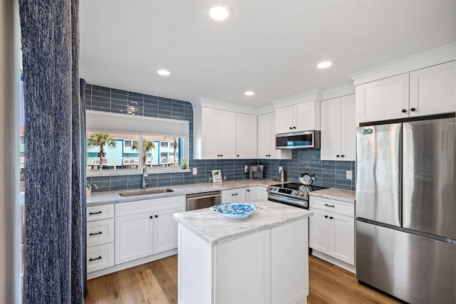 kitchen featuring stainless steel appliances, a sink, backsplash, and a kitchen island