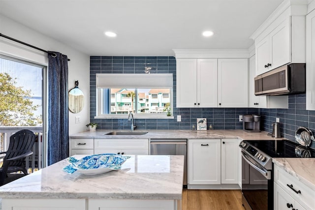 kitchen featuring tasteful backsplash, a sink, appliances with stainless steel finishes, white cabinetry, and light wood-style flooring