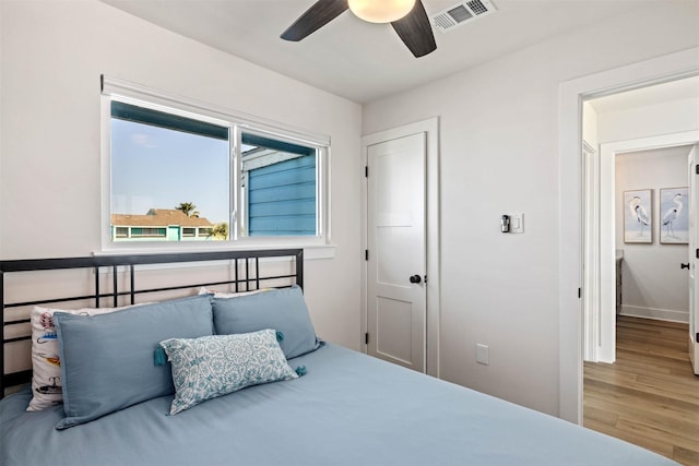 bedroom with visible vents, ceiling fan, wood finished floors, and baseboards