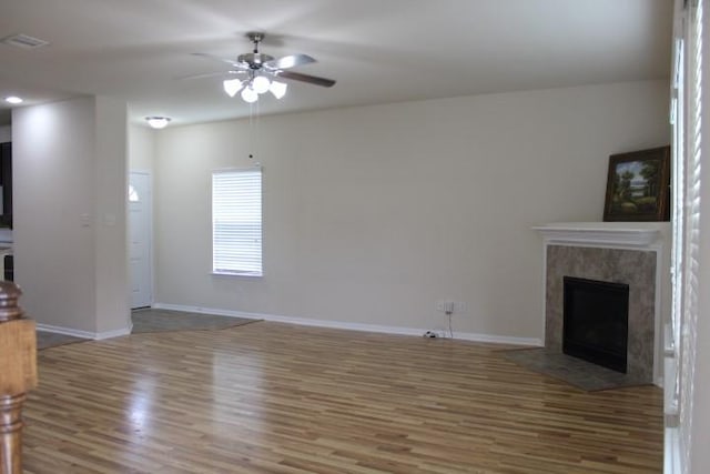 unfurnished living room featuring wood finished floors, ceiling fan, baseboards, and a fireplace