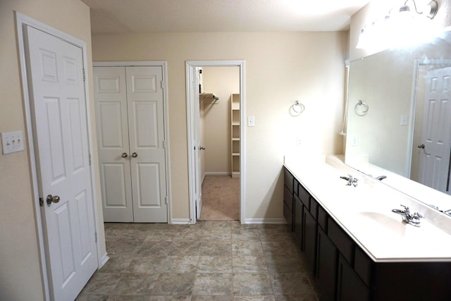 bathroom with a sink, baseboards, and double vanity