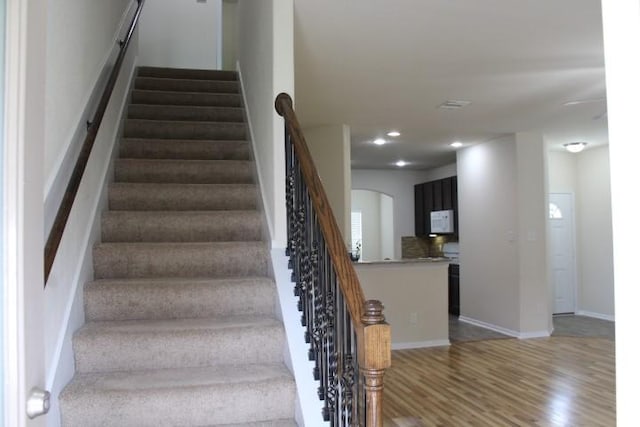 staircase with baseboards, recessed lighting, ceiling fan, arched walkways, and wood finished floors
