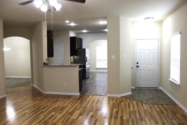 kitchen featuring dark wood-style flooring, baseboards, a ceiling fan, and arched walkways