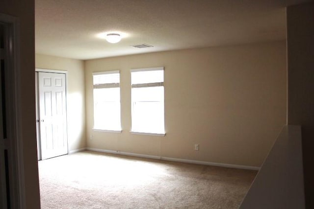 spare room with visible vents, light colored carpet, and baseboards