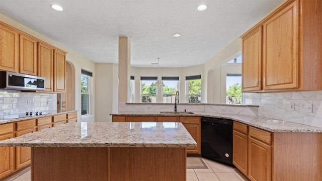 kitchen with light stone counters, a sink, a kitchen island, black appliances, and tasteful backsplash