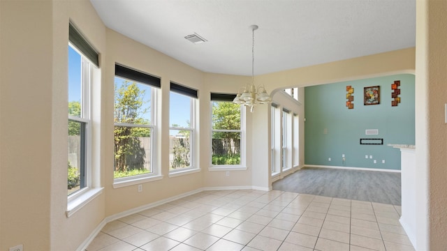 unfurnished dining area with baseboards, a notable chandelier, tile patterned flooring, and visible vents