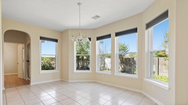 unfurnished dining area with baseboards, light tile patterned flooring, a chandelier, and visible vents