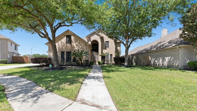 view of front of house with brick siding, fence, and a front yard