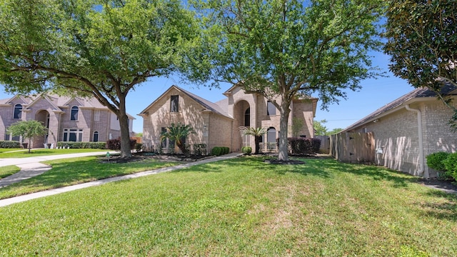 mediterranean / spanish-style house with a front lawn, brick siding, and fence