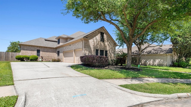 traditional home featuring a front lawn, concrete driveway, fence, a garage, and brick siding