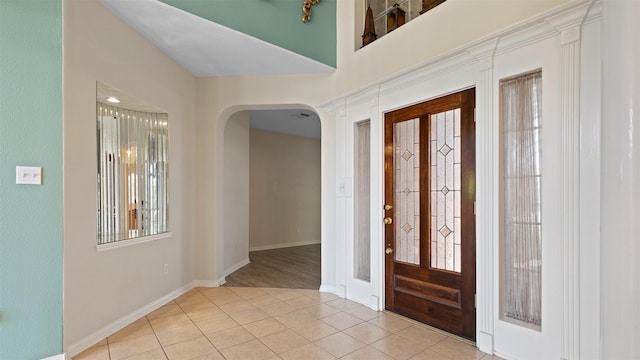 entrance foyer featuring arched walkways, tile patterned flooring, and baseboards