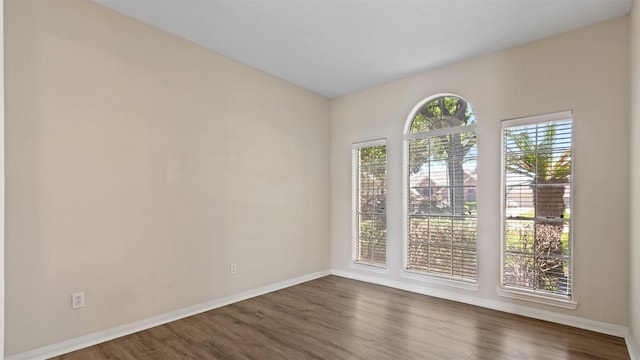 empty room with baseboards and dark wood-type flooring