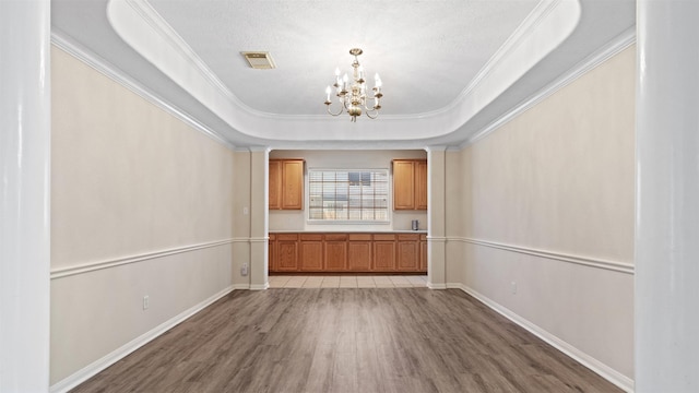 interior space with an inviting chandelier, ornamental molding, light wood finished floors, and baseboards