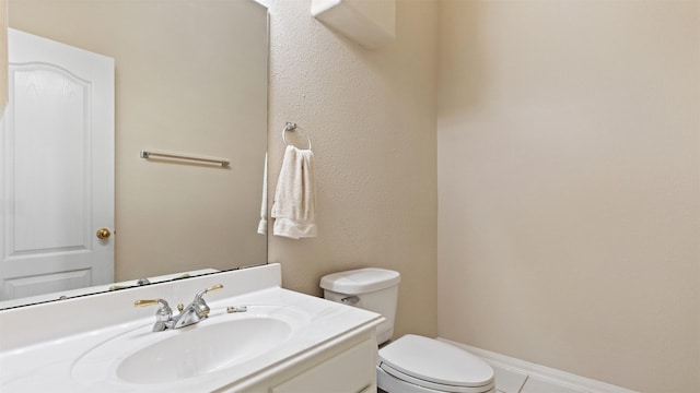 half bathroom with toilet, vanity, and tile patterned floors