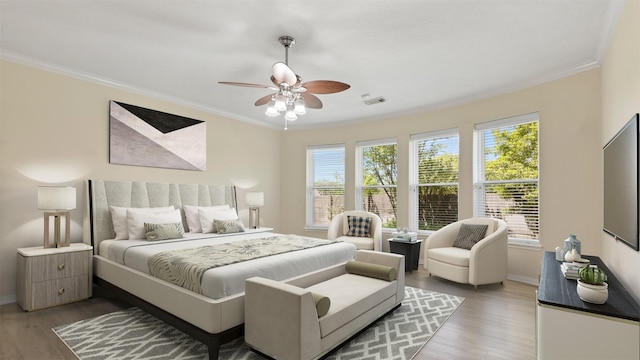 bedroom with baseboards, ornamental molding, wood finished floors, and visible vents