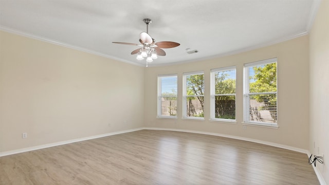 spare room featuring a ceiling fan, light wood-style flooring, baseboards, ornamental molding, and visible vents