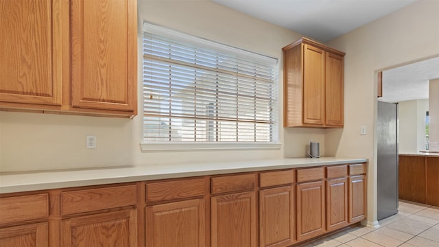 kitchen featuring light tile patterned flooring, light countertops, and brown cabinetry