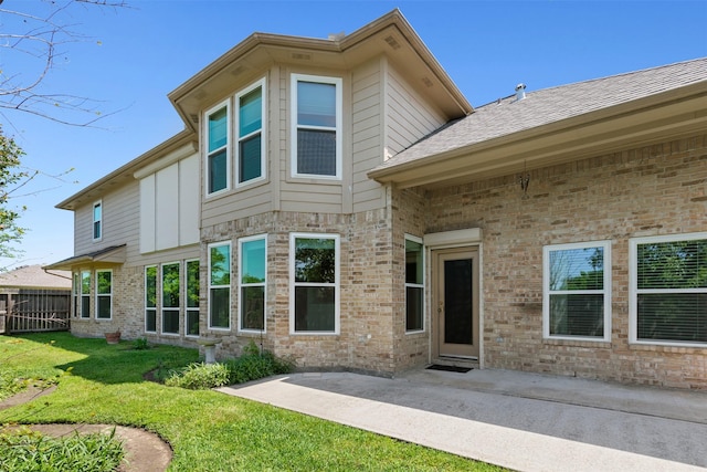 back of house featuring fence, a lawn, brick siding, and a patio