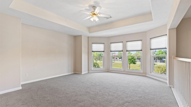 unfurnished room with baseboards, carpet floors, a ceiling fan, and a raised ceiling