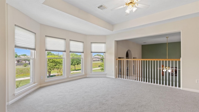 carpeted empty room with visible vents, a ceiling fan, and baseboards