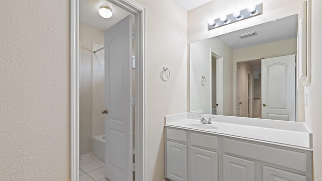 bathroom with washtub / shower combination, vanity, tile patterned floors, and visible vents