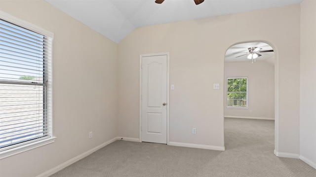 unfurnished room featuring vaulted ceiling, a ceiling fan, baseboards, and light carpet
