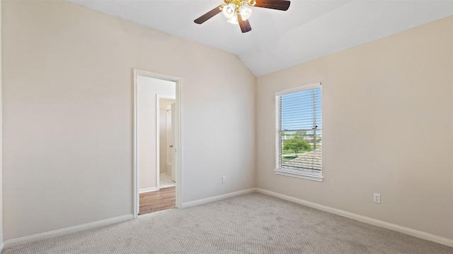 carpeted empty room with a ceiling fan, baseboards, and vaulted ceiling