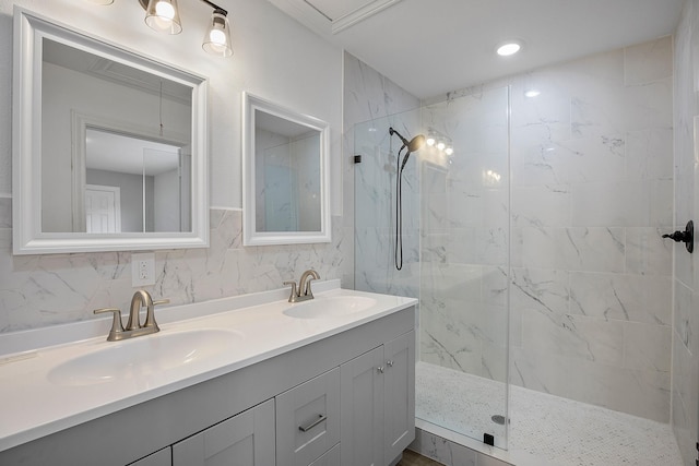 full bath featuring double vanity, a sink, and a marble finish shower