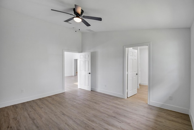 unfurnished bedroom with light wood-style flooring, baseboards, and lofted ceiling