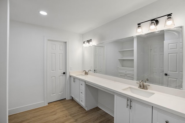 bathroom with a sink, baseboards, double vanity, and wood finished floors