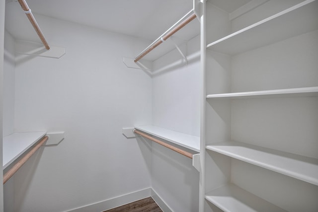 walk in closet with dark wood-style floors