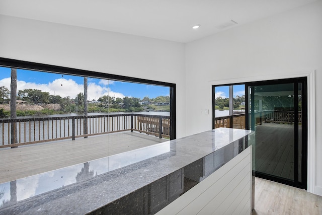 unfurnished dining area with wood finished floors, recessed lighting, visible vents, and a water view