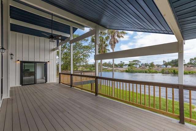 wooden deck with a yard, a ceiling fan, and a water view
