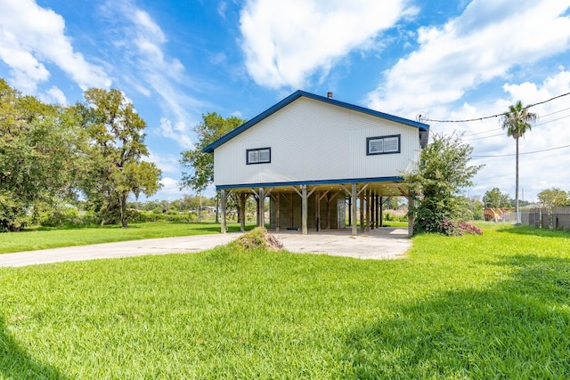 exterior space with a carport, concrete driveway, and a lawn