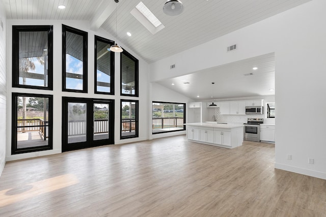 unfurnished living room featuring recessed lighting, visible vents, a skylight, high vaulted ceiling, and light wood finished floors